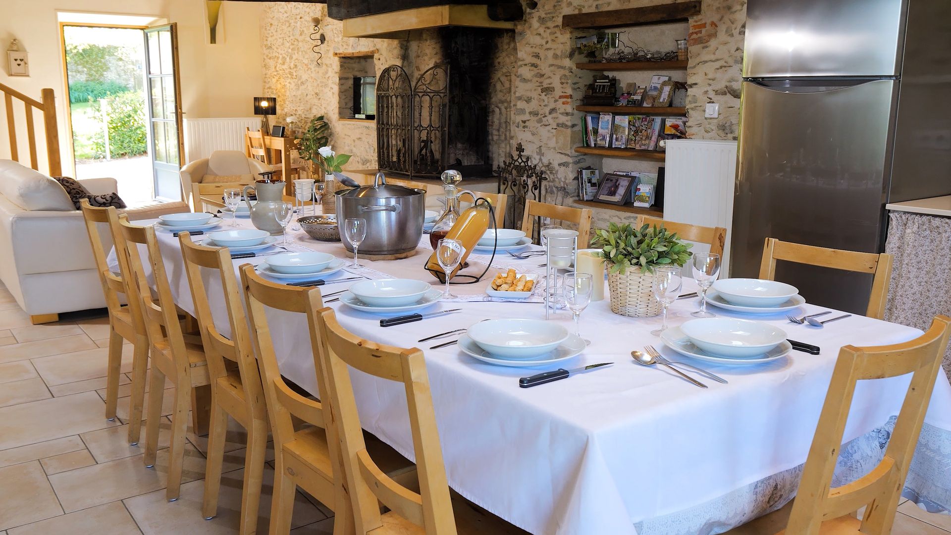 Séjour du gîte Alexandrin : grande table dressée devant la cheminée en pierre